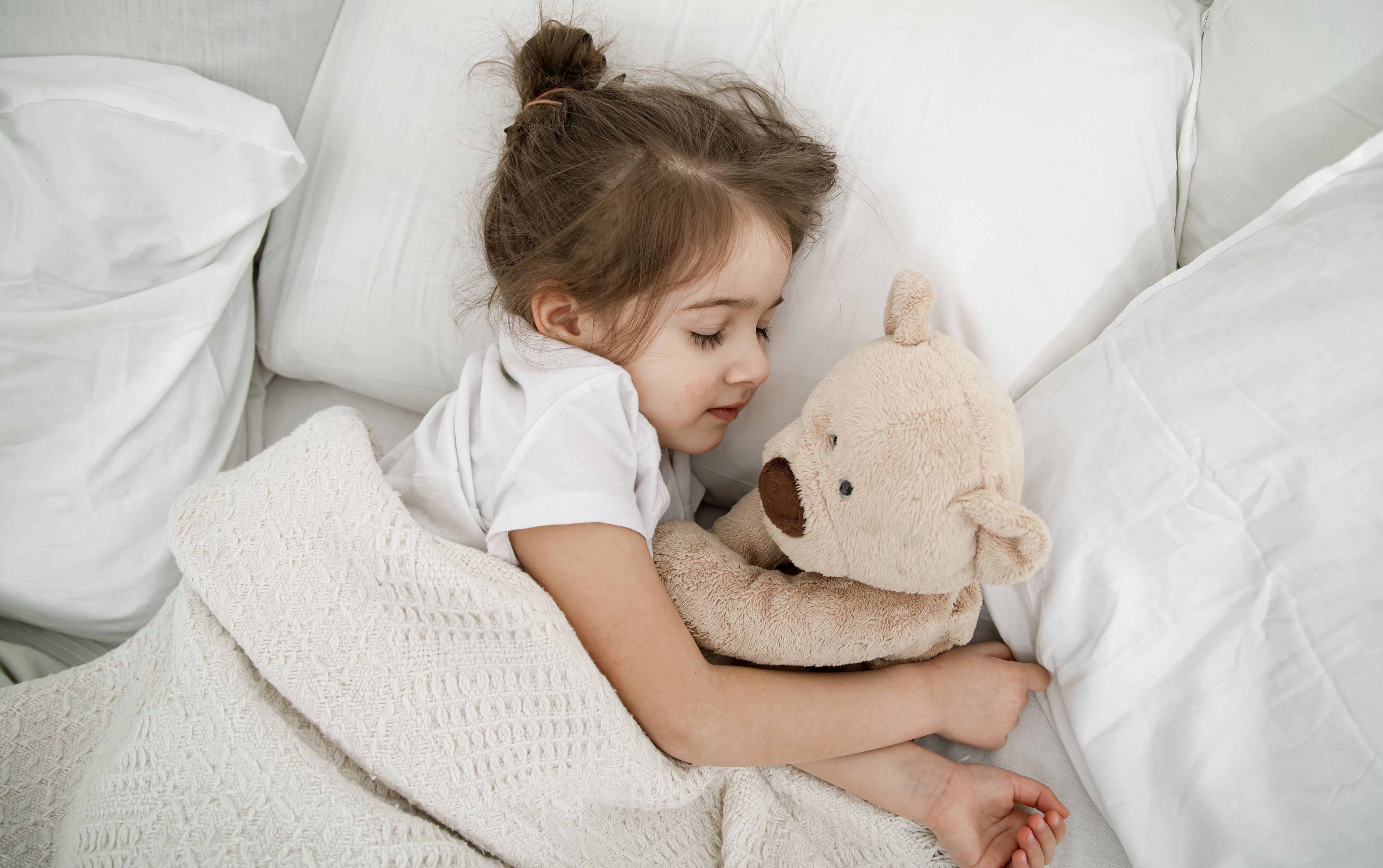 enfant qui dort paisiblement un doudou dans les bras
