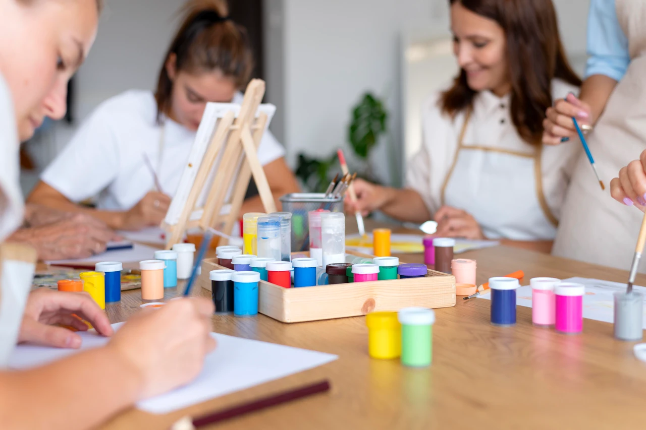 plusieurs femmes autour d'une table avec des pots de peinture pour un atelier d'art thérapie