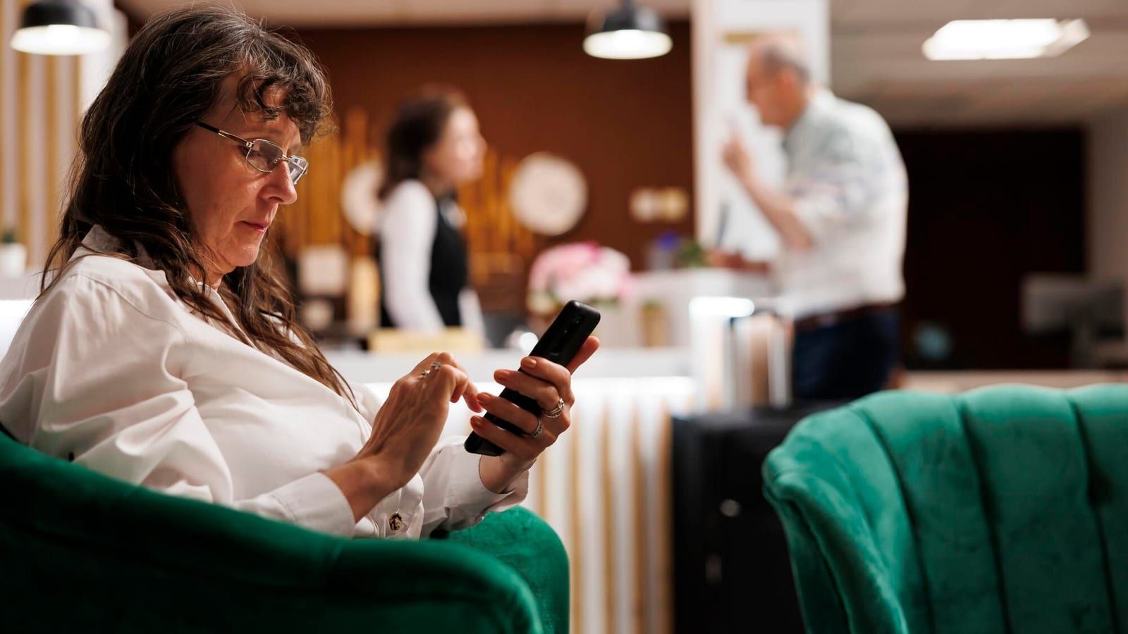 Guest using a smartphone in a boutique hotel lobby to interact with a digital concierge system