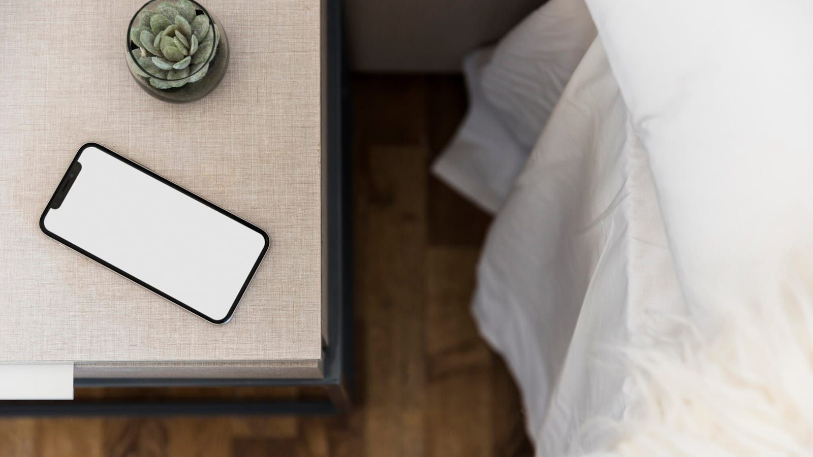 Smartphone displaying a hotel menu next to a wooden QR code stand on a bedside table