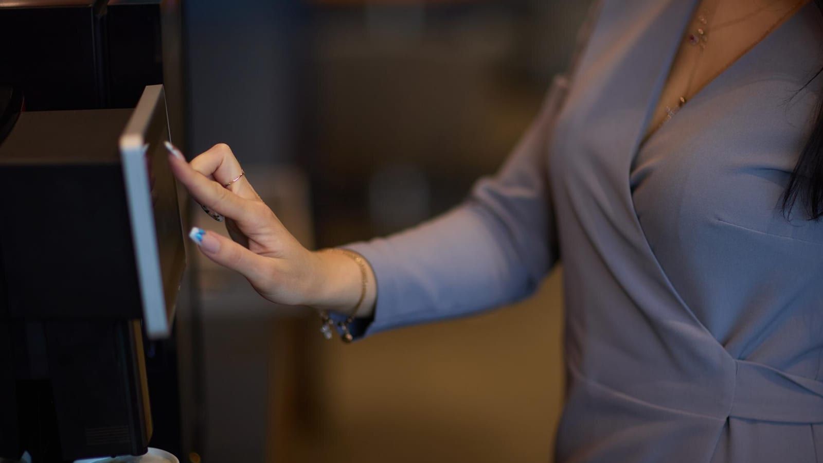 Gość hotelowy meldujący się samodzielnie przy użyciu wolnostojącego kiosku z ekranem dotykowym w jasnym lobby