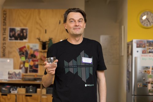 Me holding a glass of water and wearing a KiwiPyCon t-shirt