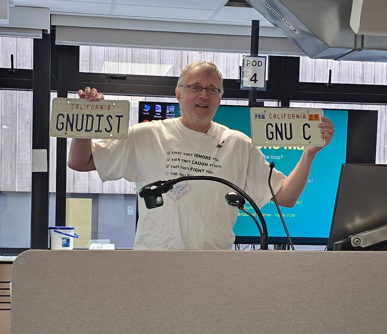 Michael holding up his GNUDIST and "GNU C" vehicle license plates from California